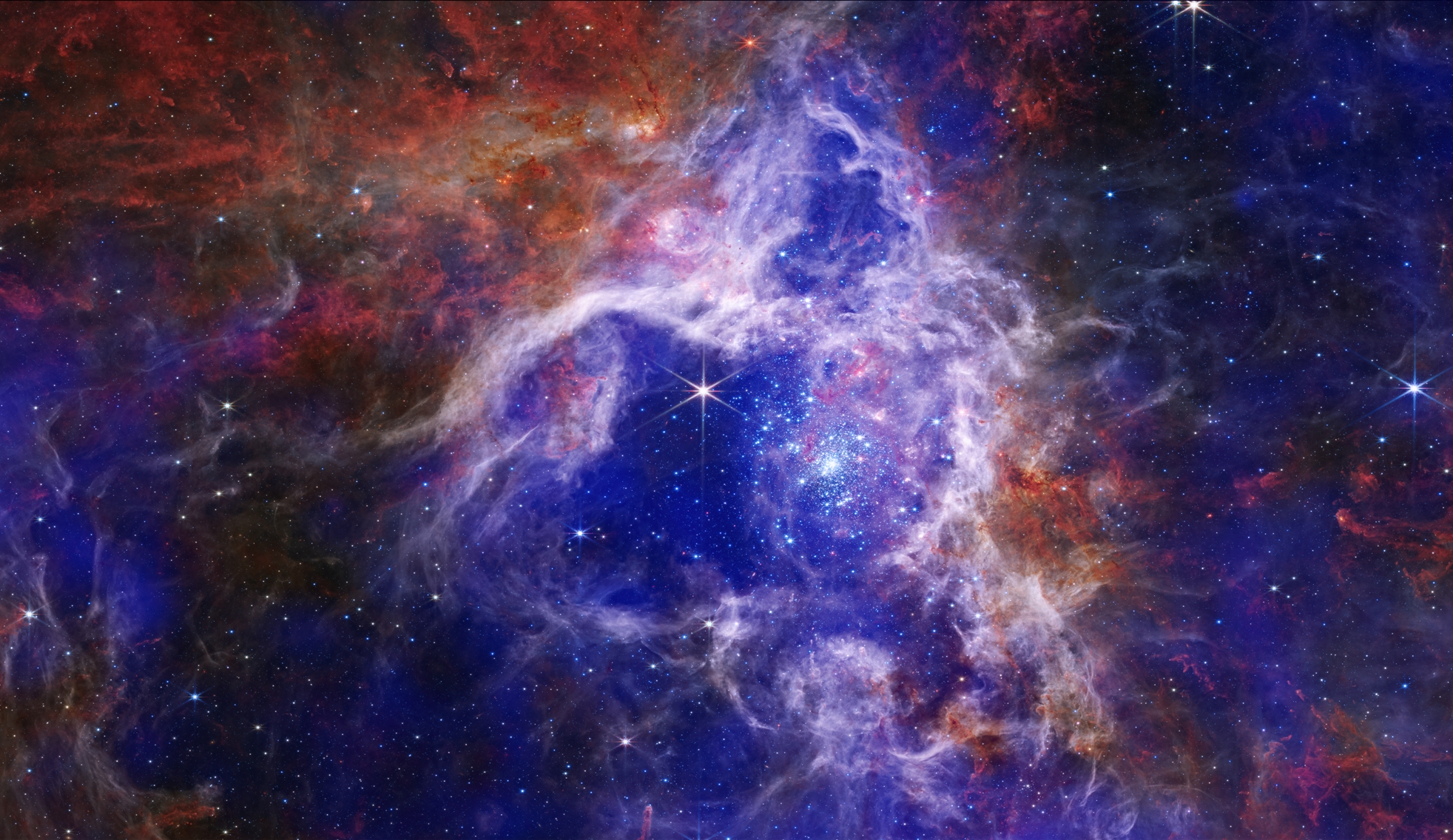 La nébuleuse de la Tarentule (également connue sous le nom de 30 Doradus, ou NGC 2070 ou Caldwell 103) est une région HII dans le Grand Nuage de Magellan. Cette nouvelle image composite combine les données en rayons X des observations Chandra de 30 Doradus avec une image infrarouge du télescope spatial James-Webb de la Nasa, publiée à l'automne 2022. Les rayons X (bleu royal et violet) révèlent du gaz qui a été chauffé à des millions de degrés par les ondes de choc — semblables aux bangs soniques des avions — générées par les vents des étoiles massives. Les données infrarouges du JWST (rouge, orange, vert et bleu clair) montrent des toiles spectaculaires de gaz plus froids qui fournissent les matières premières des futures étoiles. © Rayons X (Chandra) : Nasa/CXC/Penn State Univ./L. Townsley et coll.; IR (Spitzer) : Nasa/JPL/PSU/L.Townsley et al. IR (JWST) : équipe de production Nasa/ESA/CSA/STScI/JWST ERO ; Visible (Hubble) : Nasa/STScI)