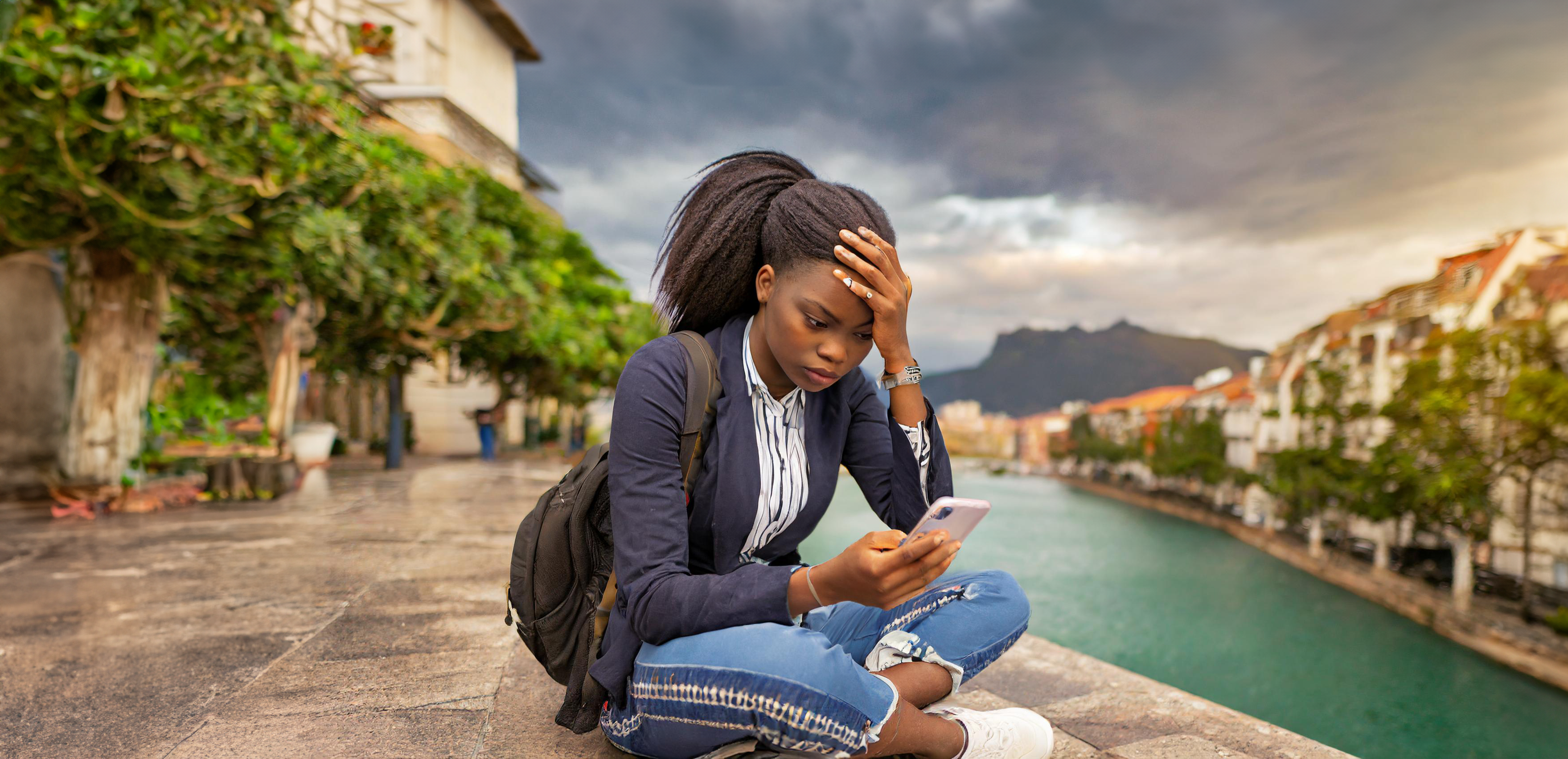 © EwaStudio, Adobe StockUne adolescente est assise sur un quai. Elle se tient la tête d'une main et de l'autre regarde son portable avec un air fatigué. © Firefly, Futura   