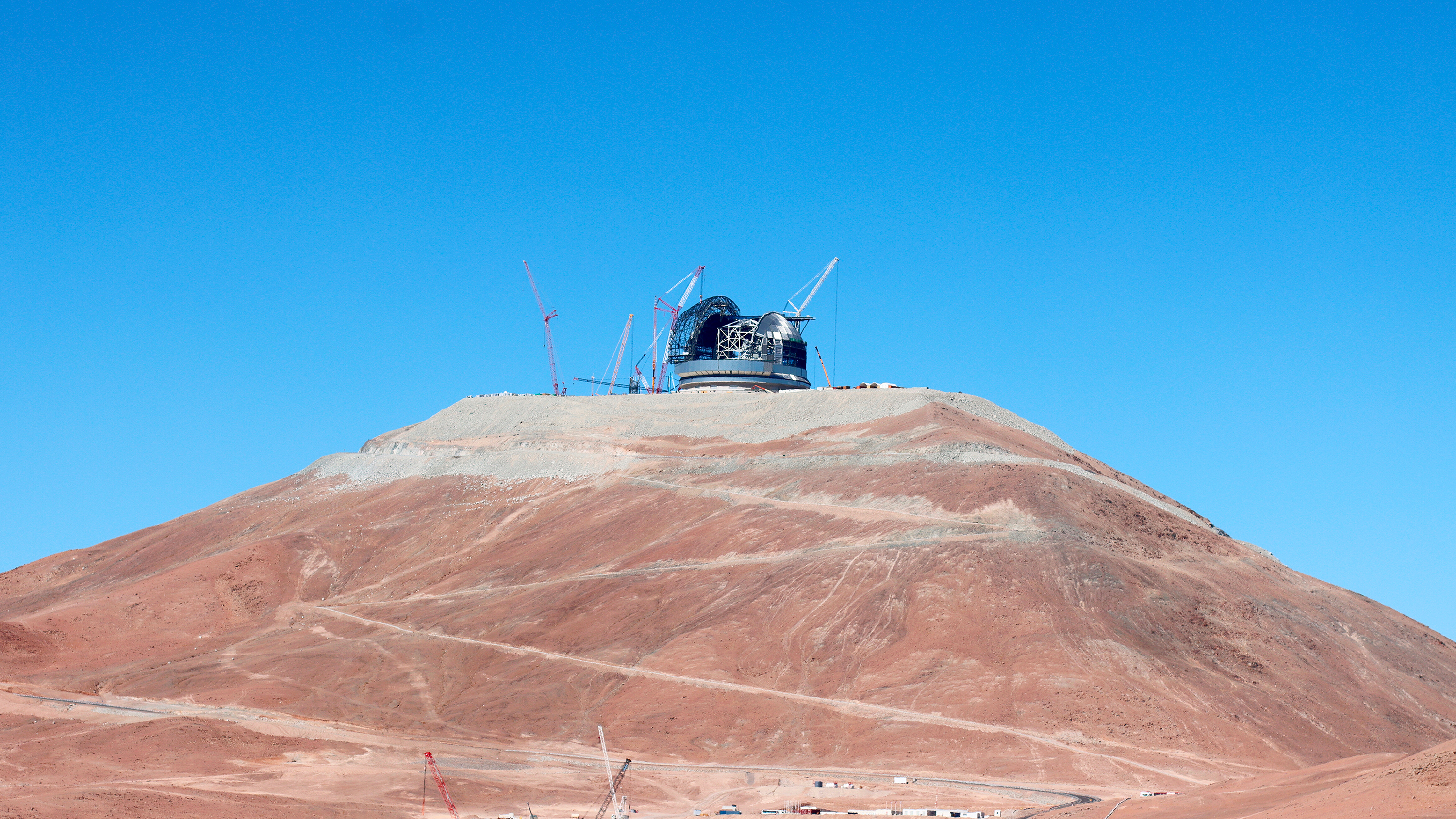 État d'avancement de la construction de l'Extremely Large Telescope (ELT) de l'ESO, au sommet du Cerro Armazones, au cœur du désert d'Atacama, au Chili. Cette photo a été prise en mars 2025 et montre plusieurs grues autour du dôme du télescope, travaillant à l'achèvement de cette énorme structure. © ESO