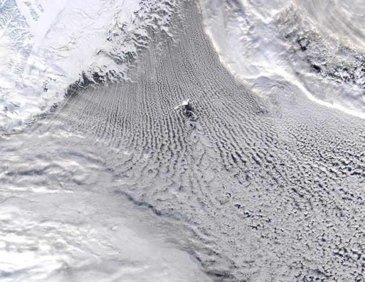 Une image prise par l'instrument Modis (Moderate Resolution Imaging Spectroradiometer), installé sur les satellites de la Nasa, Aqua et Terra. Elle montre, en vraies couleurs, une région de l'Atlantique au nord de l'Islande, autour de l'île Jan Mayen, visible au centre. On voit nettement des nuages formant des structures linéaires (les « rues de nuages »). C'est là qu'ont lieu les échanges de chaleur et d'humidité entre la mer et l'atmosphère : cette région est celle de l'Amoc (Atlantic Meridional Overturning Circulation), un mécanisme climatique qui apporte de la chaleur sur l'Europe. © GWK Moore