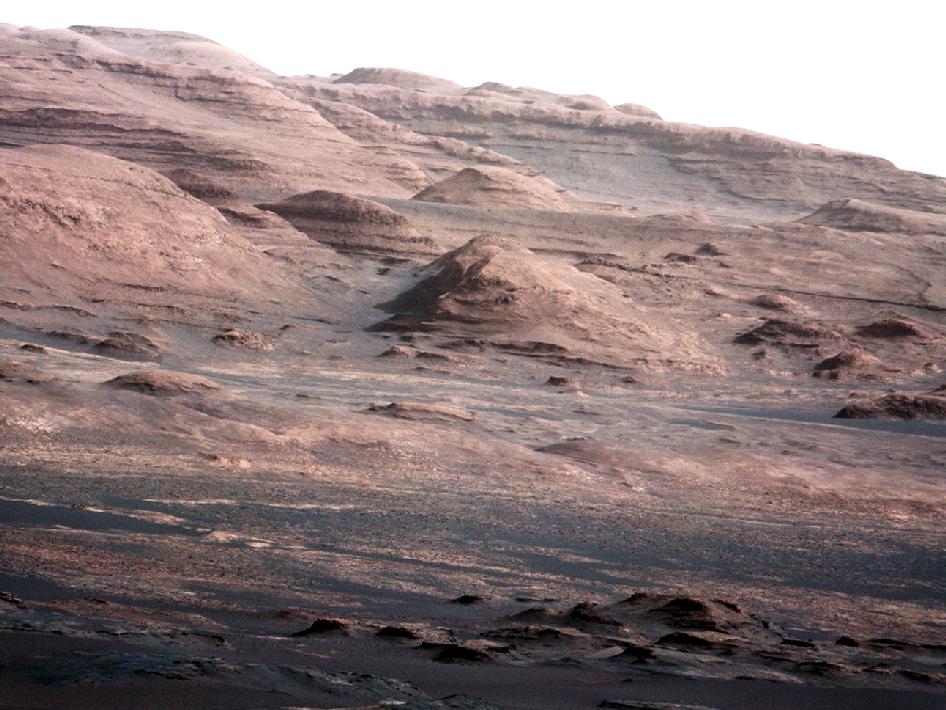 Les flancs du mont Sharp photographiés le 28 août 2012, peu après l'arrivée de Curiosity. On remarque la structure en strates. Ces dépôts sédimentaires ont probablement beaucoup de choses à nous raconter sur le passé de Mars et en particulier sur cette époque où la planète était plus chaude et plus humide. Curiosity a commencé à lire les premiers chapitres de cette histoire.&nbsp;© Nasa, JPL-Caltech