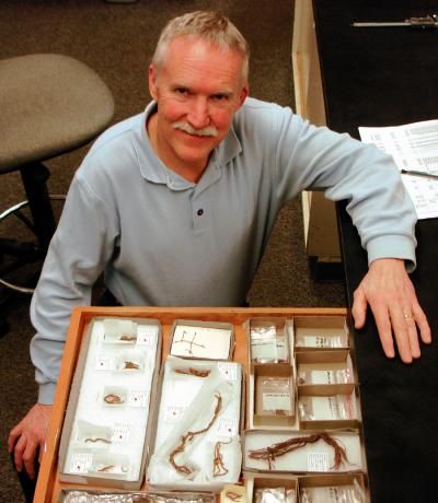 Le professeur Jenkins devant les coprolithes et autres artefacts exhumés. Crédit : University Oregon Anthropology Faculty