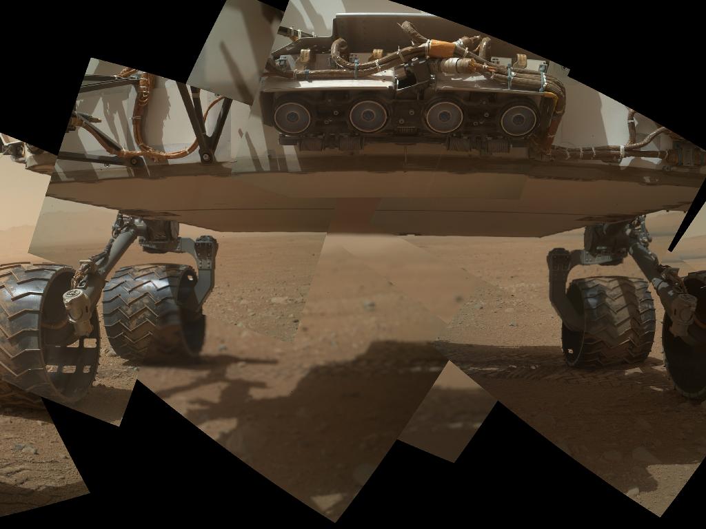 Mosaïque de photographies saisies le 9 septembre 2012 par la caméra Mahli (Mars Hand Lens Imager), fixée au bout du bras articulé du rover. Les quatre cercles au premier plan sont les Hazcam (Hazard-Avoidance cameras). Verticalement, environ 60 centimètres séparent le sol martien du châssis de Curiosity. © Nasa/JPL-Caltech/Malin Space Science Systems
