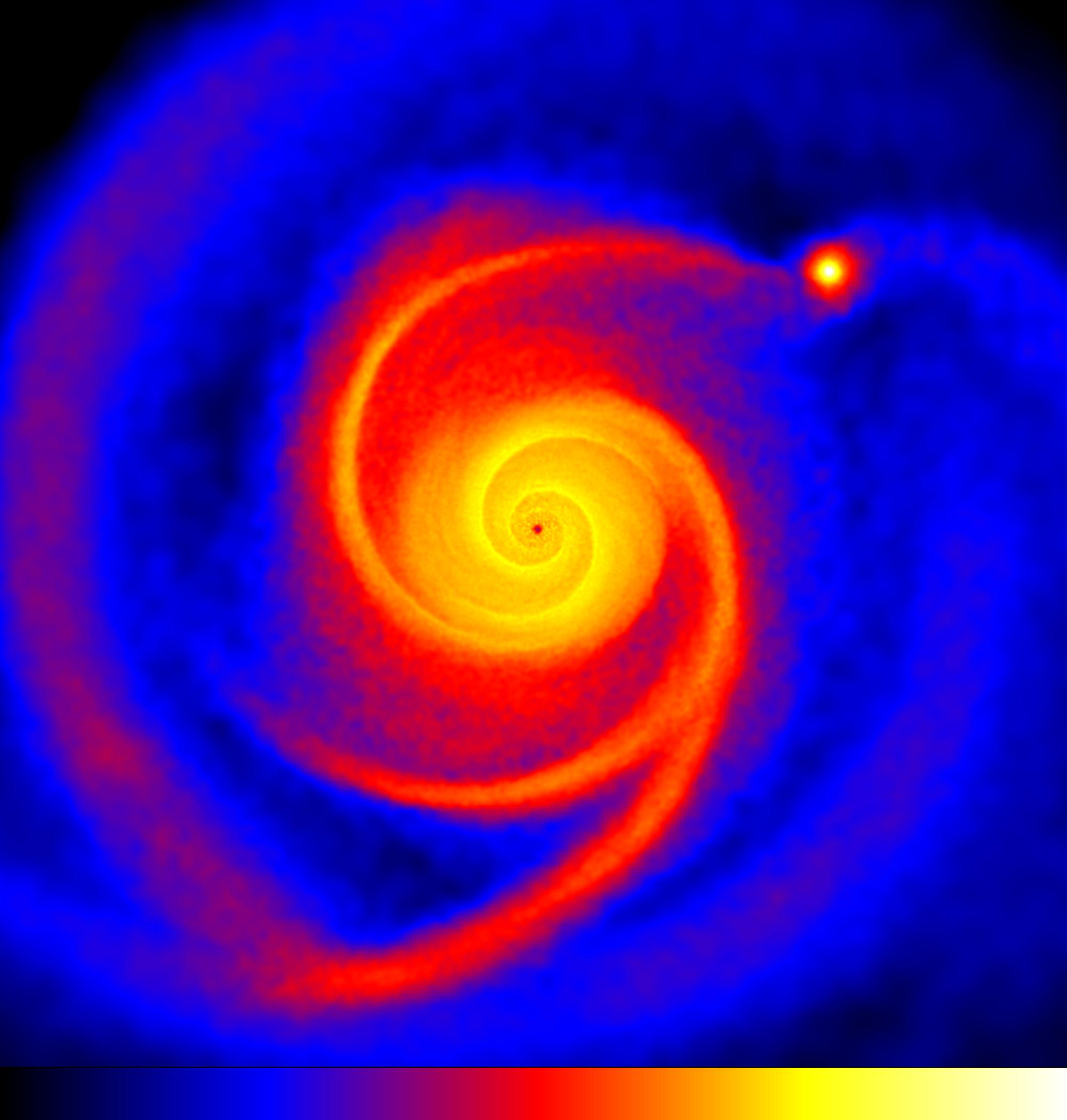 Figure 2. La simulation numérique de la formation de HL Tau B. Du bleu au rouge, les zones du disque sont de plus en plus denses en gaz, poussières et particules de la taille d'un caillou. Crédit : Greaves, Richards, Rice & Muxlow 2008