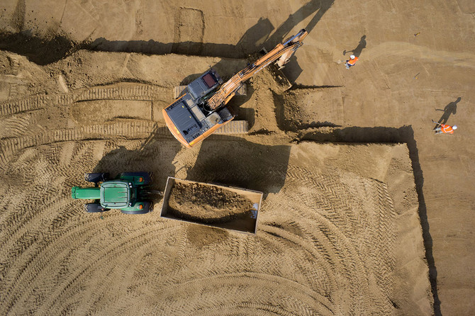 Les opérations de décapage : l'archéologue (à droite) surveille le travail des engins, la pelle charge les terres dans le tracto-benne qui les videra en dehors de l'emprise de la fouille. © Denis Gliksman, Inrap