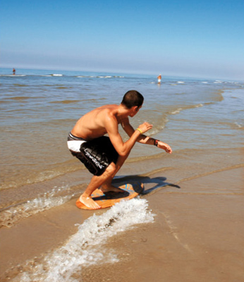 Photographie d’un skimboarder. Le fin film d’eau présent entre le sable et sa planche diminue drastiquement la force de frottement. © DR
