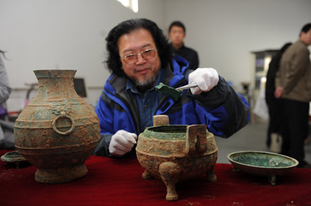 Liu Daiyun, archéologue, montre ce qui ressemble à un os animal, sorti de ce chaudron en bronze daté de 2.400 ans. © CFP