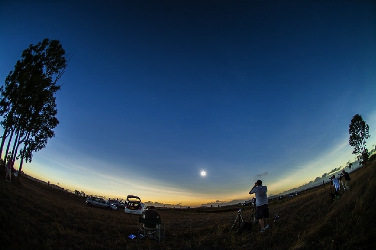 Phase totale de l'éclipse : le spectacle est grandiose, il fait de nouveau nuit 2 heures après le lever du soleil en Australie. Autour du masque lunaire se déploie la couronne solaire et l'horizon illuminé marque les limites du cône d'ombre.&nbsp;© Alan Dyer