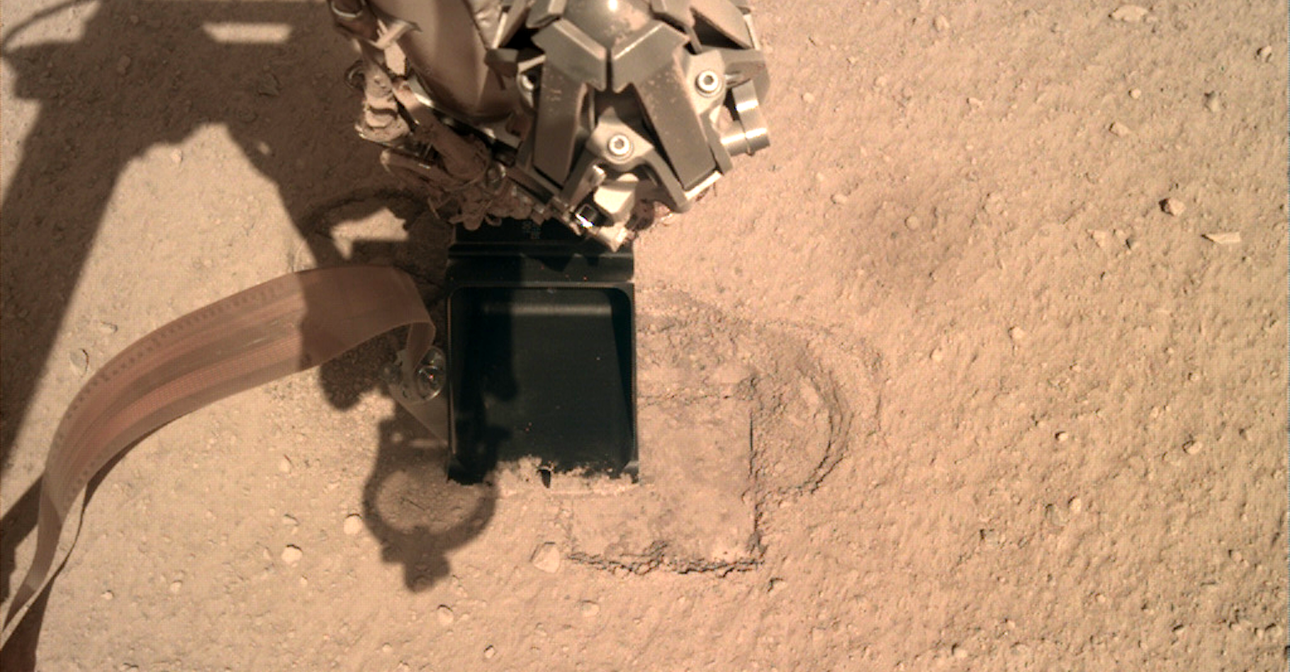Ici, le bras robotisé de l’atterrisseur InSight qui presse le capteur de flux thermique HP3 afin de lui offrir la résistance suffisante à lui permettre de creuser le sol de Mars. © Nasa, JPL-Caltech