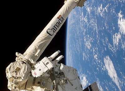 Le bras manipulateur Canadarm au cours de la mission STS-110. On distingue bien le revêtement thermique et l'astronaute légèrement en avant-plan donne l'échelle. Crédit Nasa.