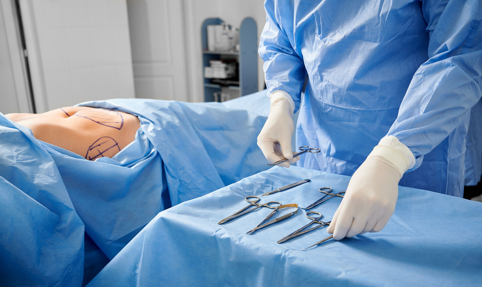 Chirurgien en gants stériles préparant des instruments médicaux,&nbsp;prêt à intervenir sur un patient. © Anatoliy_gleb, Adobe Stock