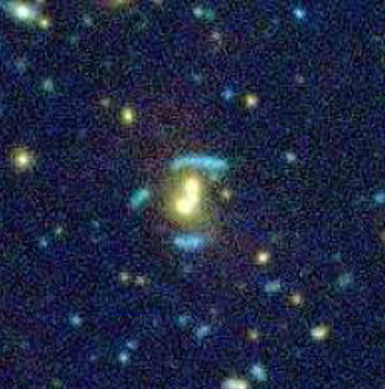 Exemple de mirage gravitationnel dans un groupe de galaxies découvert dans les images profondes du sondage CFHT-LS.  Ce mirage est provoqué parun groupe de galaxies (SL2SJ021408-053532), visible au centre de l'image en jaune. &copy; CFHT. CNRS/INSU.