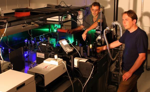 Christoph Boehme et John Lupton en train d'utiliser un laser pour bombarder un échantillon de MEH-PPV. Crédit : Nick Borys