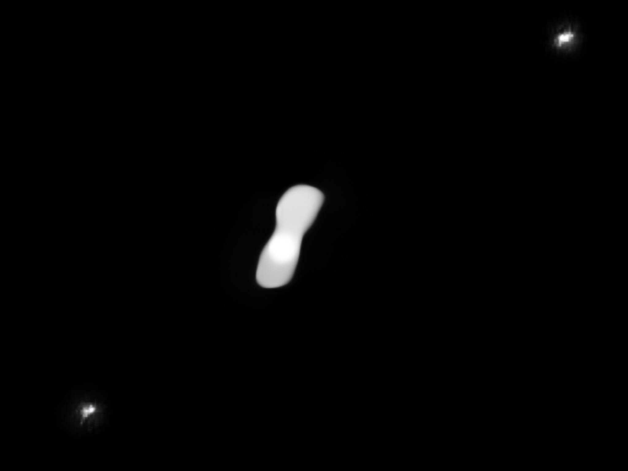 Sur cette image traitée, basée sur des observations effectuées au mois de juillet 2017, figurent les deux lunes de l'astéroïde Kleopatra (l'objet blanc central), AlexHelios et CleoSelene, qui apparaissent tels deux petits points blancs dans les angles supérieur droit et inférieur gauche de l'image. Les lunes de Kleopatra sont difficiles à observer sur les images brutes – acquises au moyen de l’instrument Sphere (Spectro-Polarimetric High-contrast Exoplanet Research) installé sur le VLT de l'ESO – en raison de l'éblouissement autour de l'astéroïde, inhérent à ce type d'observations par optique adaptative. L’obtention de cette vue a nécessité le traitement des images de Kleopatra afin de supprimer les reflets et de révéler la présence des lunes. © ESO/Vernazza, Marchis et al./Mistral&nbsp;algorithm (Onera/CNRS)