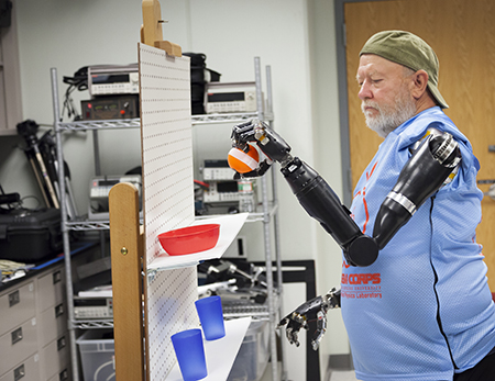 Amputé des deux bras, Les Baugh déplace un objet en contrôlant ses prothèses par la pensée. © Johns Hopkins University Applied Physics Laboratory