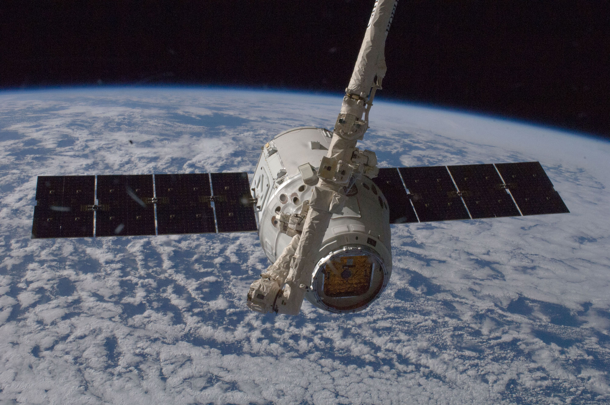 Une capsule Dragon capturée par le bras robotique de la Station spatiale internationale pour être amarrée à son module Harmony. © Nasa