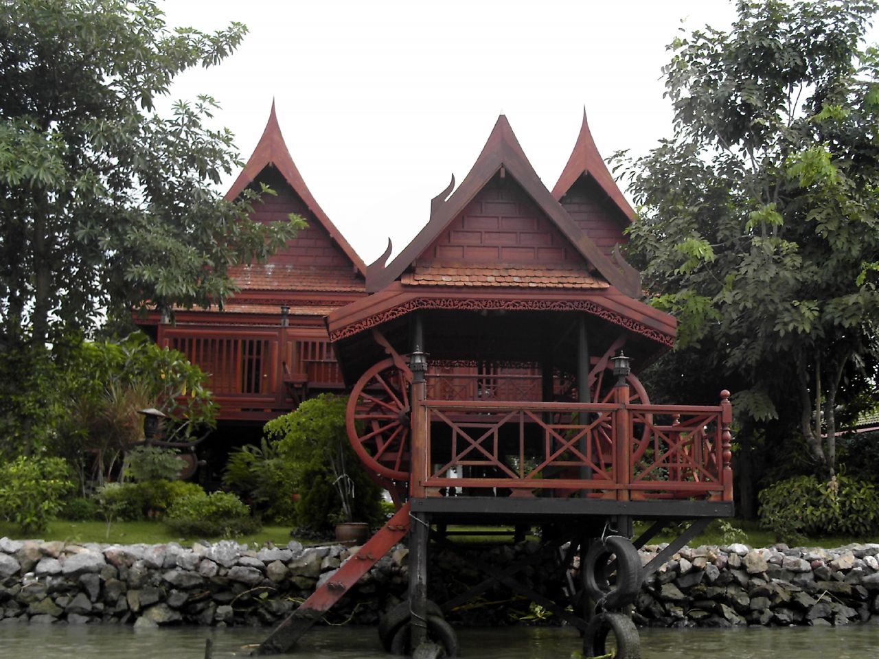 Maison en bois rouge sur pilotis, en Thaïlande
