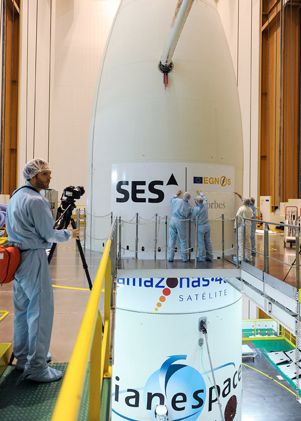 La traditionnelle pose des logos des satellites sur la coiffe du lanceur a lieu ici sur celle d’une Ariane 5 ECA. Elle mettra en orbite deux satellites de télécommunications. © Esa, Cnes, Arianespace, service optique CSG