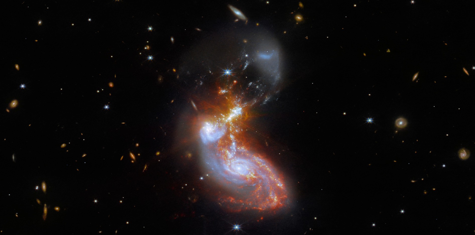 Brillante aux longueurs d'onde infrarouges, cette paire de galaxies en fusion se trouve à environ 500 millions d'années-lumière dans la constellation du Dauphin. La collision cosmique est vue sur un fond de galaxies encore plus lointaines. La fusion de galaxies elle-même s'étend sur environ 100 000 années-lumière dans cette image profonde du télescope spatial James-Webb. Les données d'image proviennent de la caméra en proche infrarouge (NIRCam) et de l'instrument pour l'infrarouge moyen (Miri) de Webb. © ESA Webb, Nasa CSA, L. Armus, A. Evans