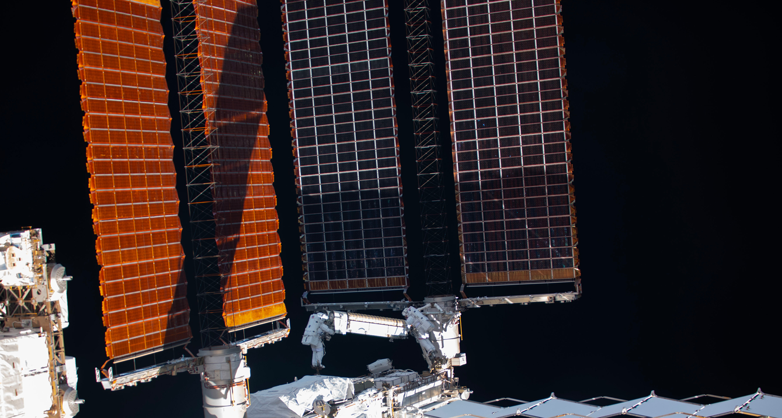 Cette image, acquise depuis l'intérieur de la Station spatiale internationale, permet de se rendre compte de la taille des panneaux solaires du complexe orbital. Thomas Pesquet et Shane Kimbrough sont à la manœuvre pour installer le premier panneau solaire iRosa. © Nasa