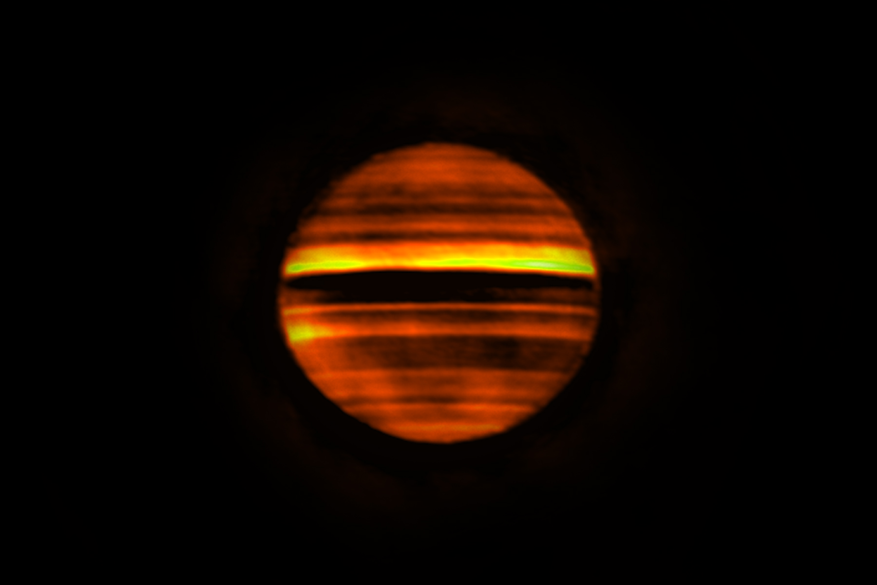 Voici en fausses couleurs une image radio de Jupiter réalisée avec Alma. Les bandes lumineuses indiquent les températures élevées et les bandes sombres les températures basses. Les bandes sombres correspondent aux zones sur Jupiter, qui sont souvent blanches aux longueurs d'onde visibles. Les bandes lumineuses correspondent aux ceintures brunes de la planète. Cette image contient plus de 10 heures de données, soit le temps que met Jupiter pour effectuer sa rotation. Par conséquent, la combinaison de ces données trahit la rotation de la planète qui a rendu les détails flous. © Alma (ESO/NAOJ/NRAO), I. de Pater et al.; NRAO/AUI NSF, S. Dagnello