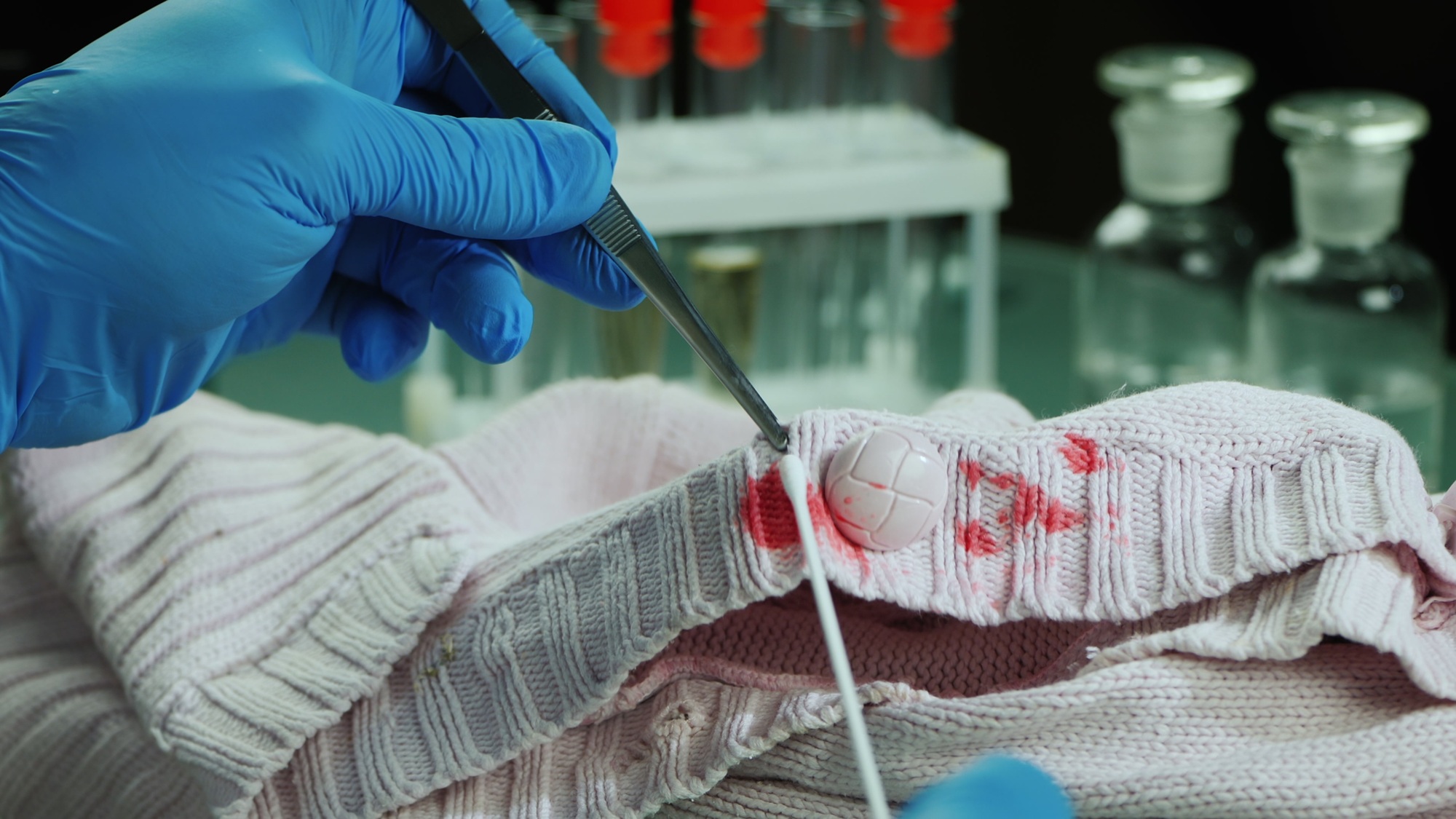 Le médecin légiste, muni de gants stériles, de pince, d'éprouvette et autre matériel médical spécialisé, réalise des prélèvements afin de déterminer les causes d'un décès et comprendre son contexte. © StockMediaProduction, Adobe Stock.
