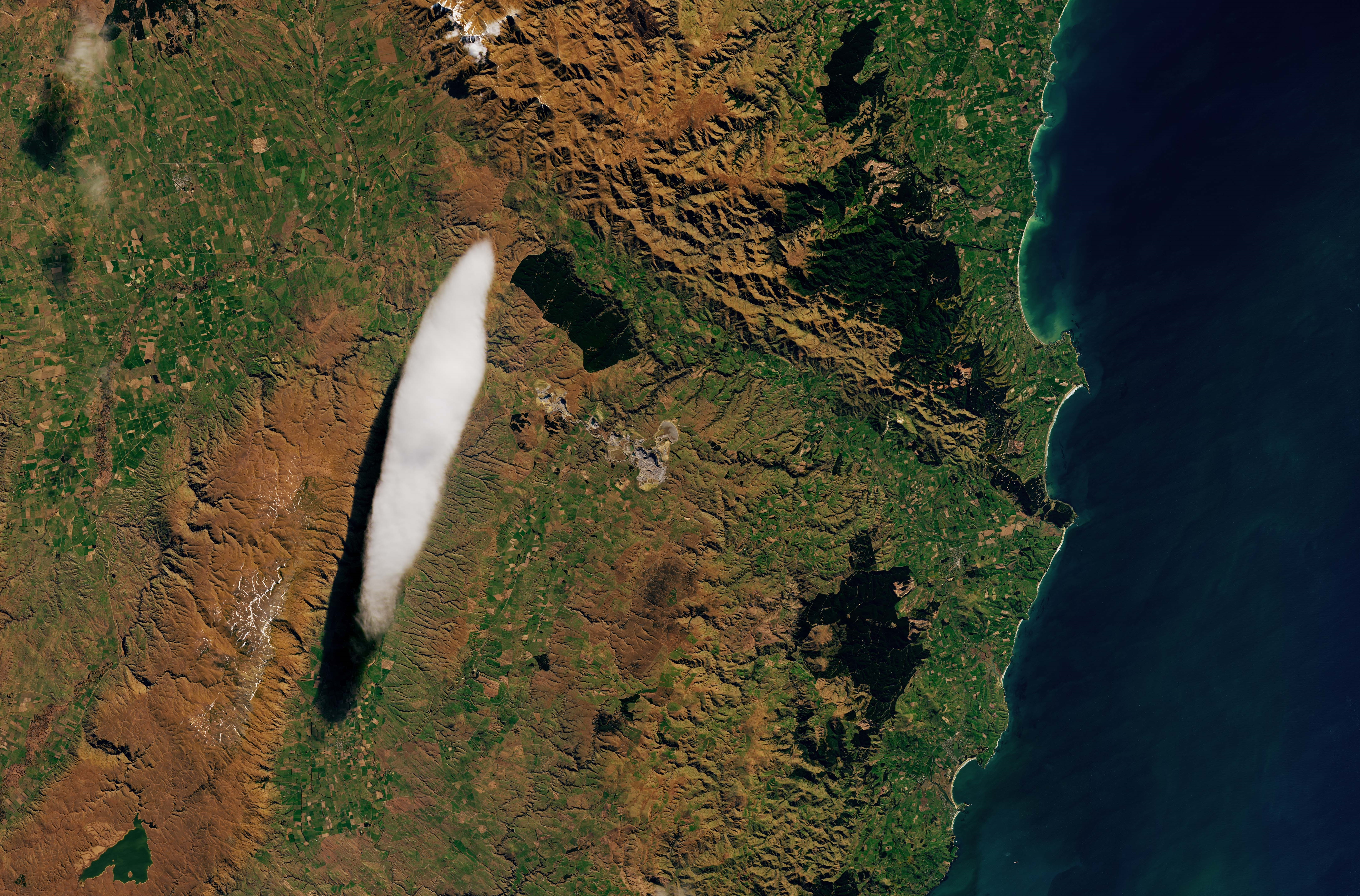 Le nuage lenticulaire pris en photo le 7 septembre 2024 en Nouvelle-Zélande : à gauche de celui-ci, on aperçoit la chaîne de montagne qui contribue à sa formation (en marron clair). © Nasa