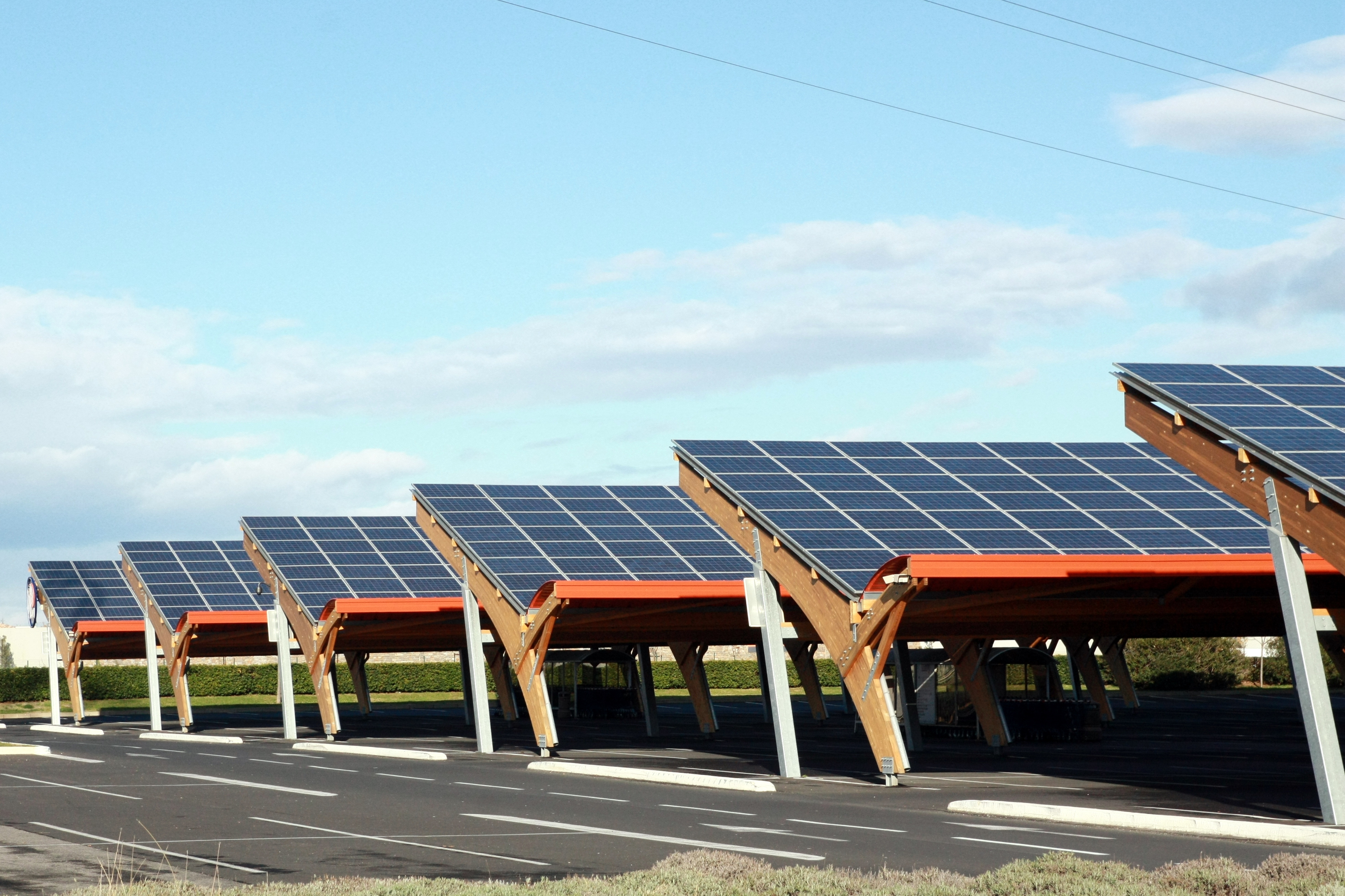 Sur une aire de parking, une ombrière photovoltaïque offre l'avantage de production d'énergie verte tout en protégeant les véhicules y stationnant. © illustrez-vous, Adobe Stock