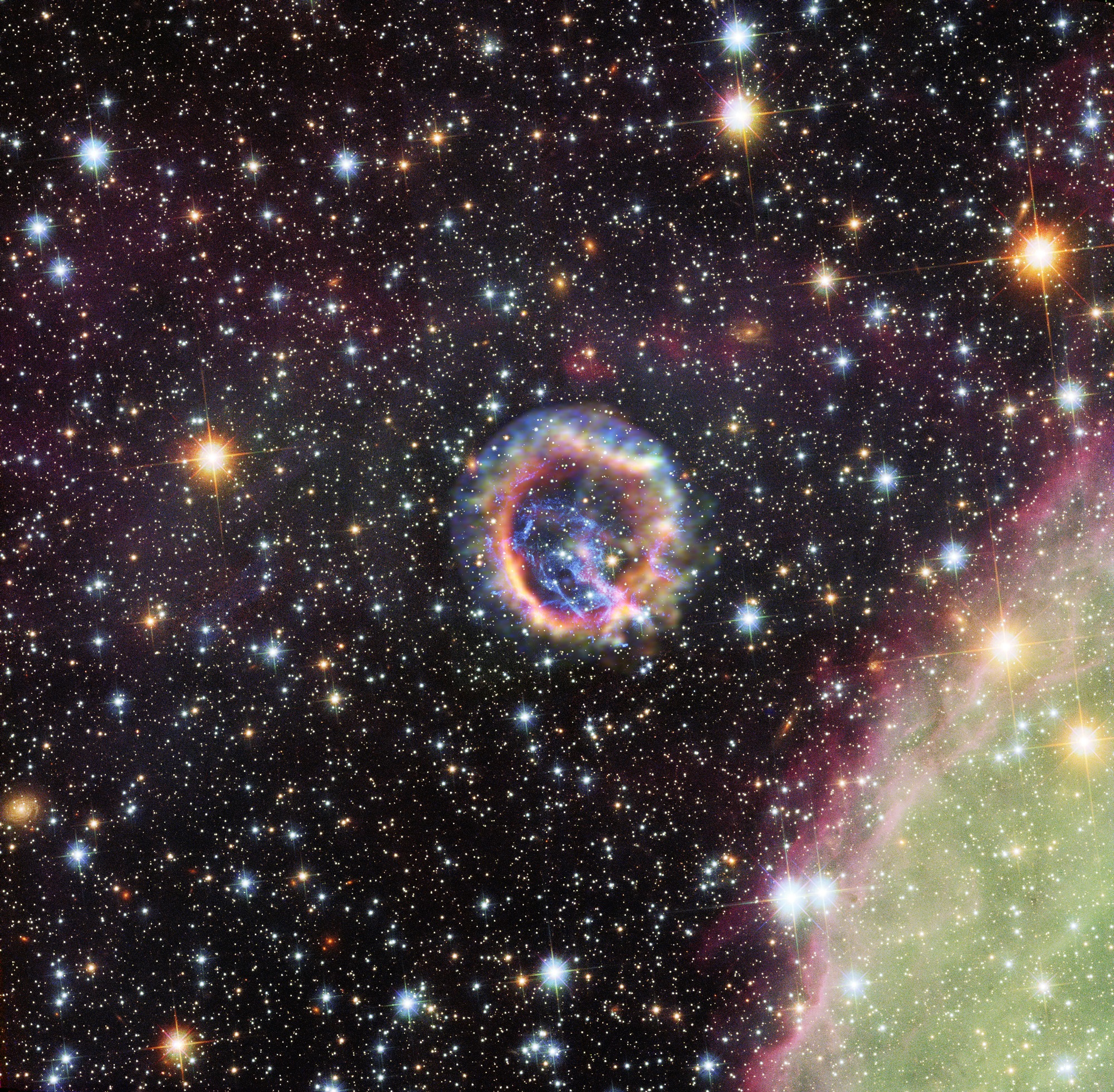 Le rémanent de supernova E0102 dans le Petit Nuage de Magellan, galaxie naine satellite de la Voie lactée située à environ 190.000 années-lumière de nous. Cette supernova était visible dans le ciel de l'hémisphère sud il y a environ 1.000 ans. C'est grâce à ce genre d'explosion d'une étoile massive en fin de vie que l'Univers s'enrichit en éléments radioactifs lourds. © X-ray (NASA/CXC/ESO/F.Vogt et al.); Optical (ESO/VLT/MUSE), Optical (NASA/STScI)