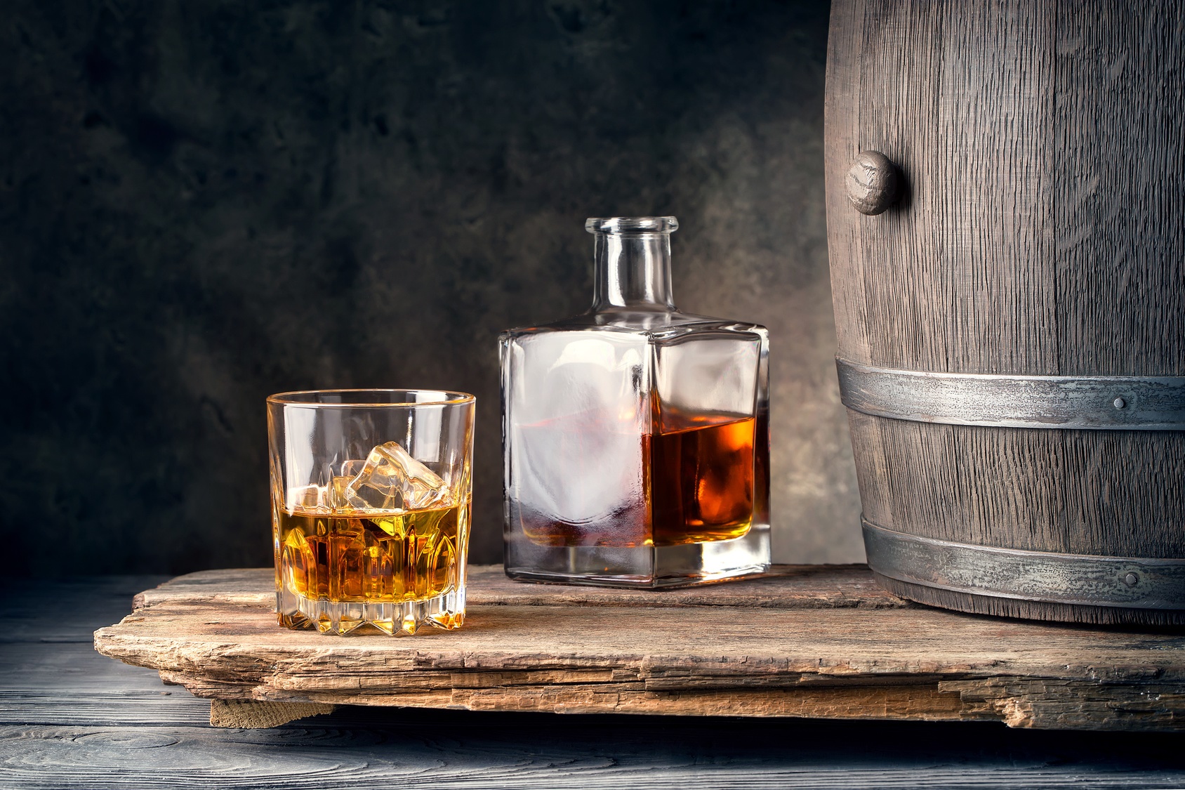 Un flacon et un verre de whisky placés à côté d'un tonneau de distillation. © alexlukin, Fotolia      