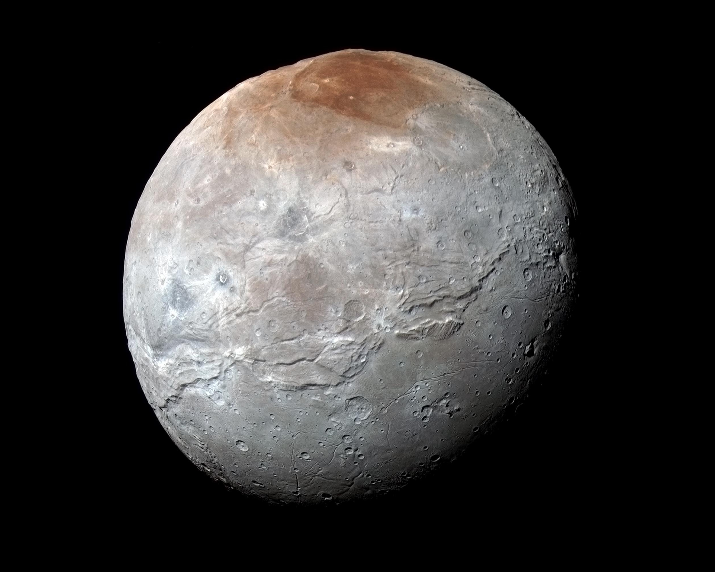 Charon, le «&nbsp;nocher des Enfers&nbsp;», le passeur du fleuve Styx, photographié par New Horizons le 14 juillet 2015, juste avant le survol de Pluton. Les images prises à travers les filtres infrarouge, rouge et bleu de l’instrument Ralph/MVIC révèlent les différentes compositions des terrains. La région du pôle nord a été baptisée Mordor Macula. La longue faille qui parcourt l’astre sur plus de 1.800&nbsp;km le long de son équateur est nommée Serinity Chasma. La résolution est de 2,9&nbsp;km par pixel. © Nasa, JHUAPL, SwRI