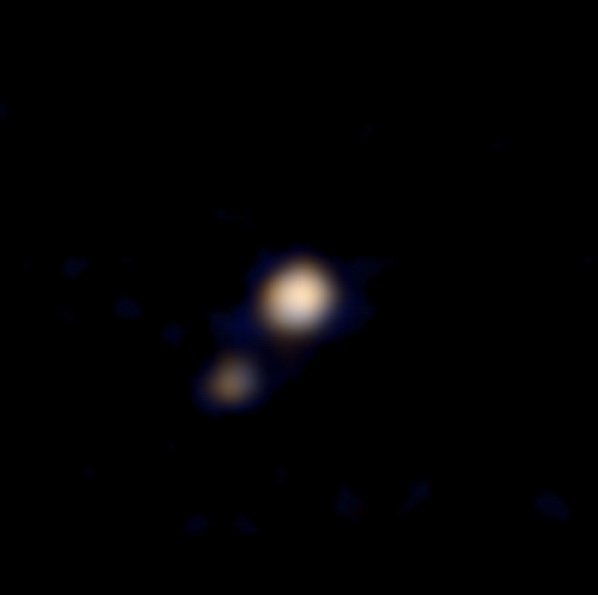 Le système Pluton-Charon photographié le 9 avril 2015 par l’instrument Ralph à bord de la sonde New Horizons à 115 millions de km (la distance Soleil-Vénus). Derrière la même optique, Ralph comporte en fait deux instruments, dont le MVIC, Multicolor Visible Imaging Camera, sensible dans le domaine visible et dans le proche infrarouge, à qui l'on doit ce premier double portrait en couleurs. Il est flou mais augure bien de la qualité des observations effectuées lors du survol du 14 juillet prochain. Au plus près de Pluton, à environ 12.500 km, la résolution de Ralph/MVIC atteindra&nbsp;5 km par pixel en couleurs et 500 m en monochrome. © Nasa, Johns Hopkins University Applied Physics Laboratory (JHUAPL), Southwest Research Institute